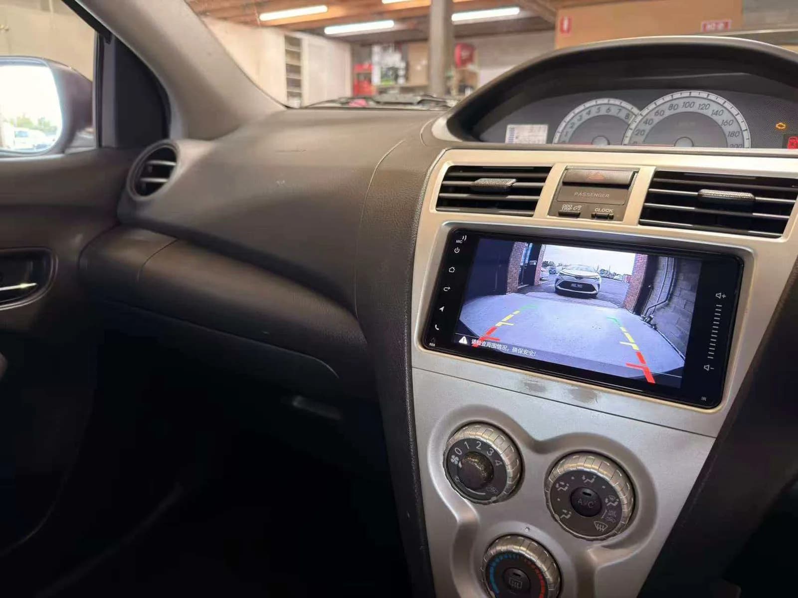 Aftermarket head unit in a Toyota Yaris showing reverse camera feed with parking guidelines