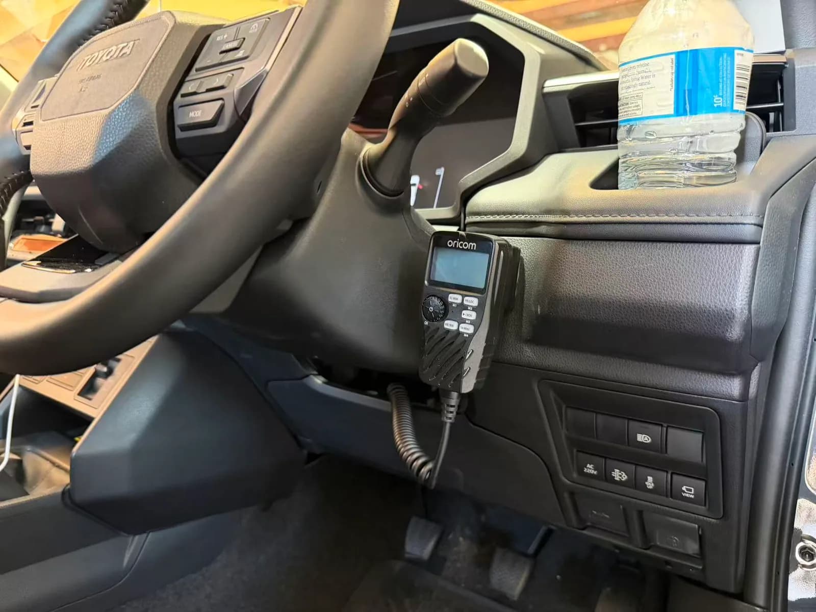 Oricom UHF radio handpiece mounted beside the steering column in a 2026 Toyota HiLux