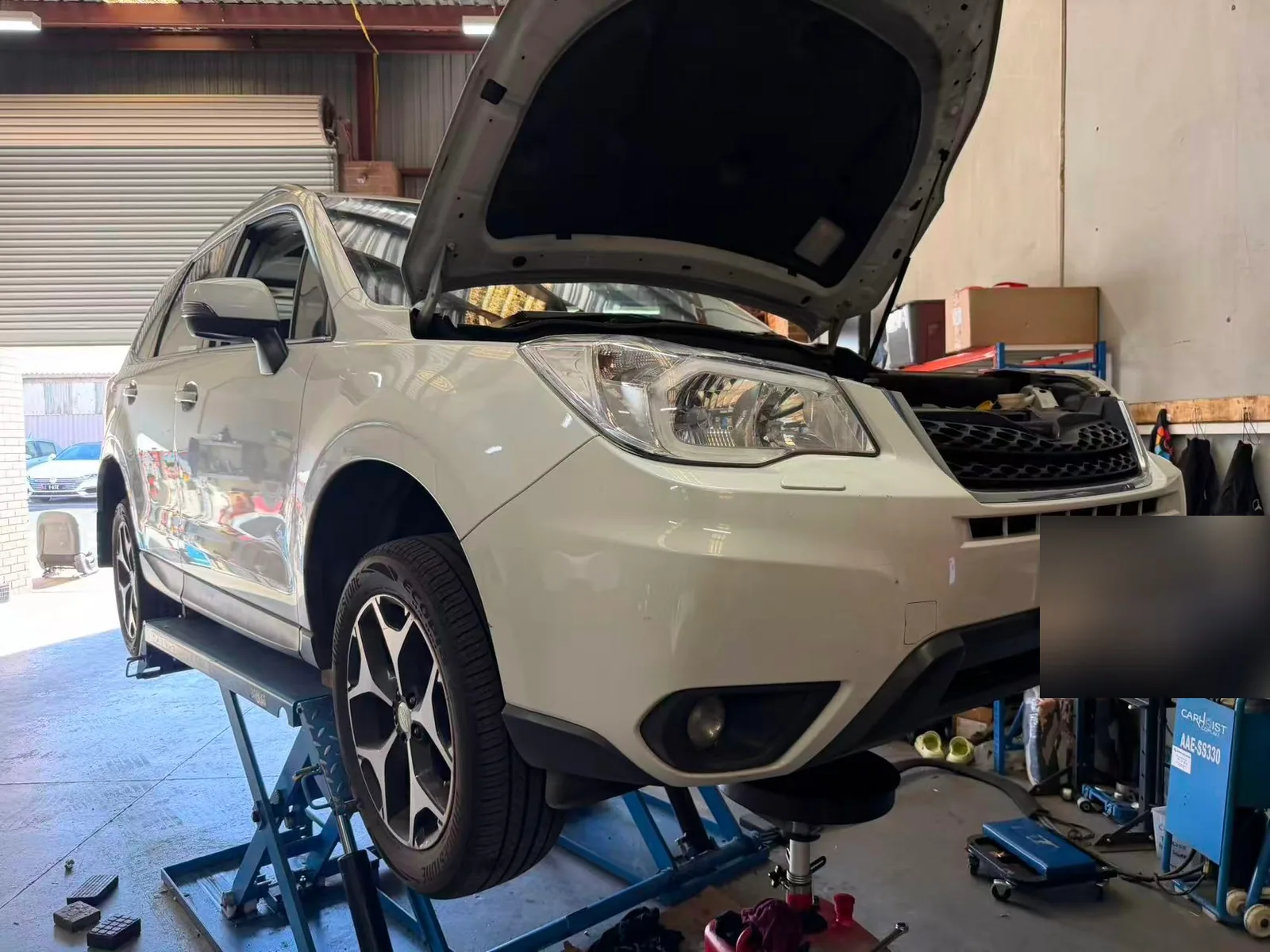 Subaru Forester raised on a workshop lift for scheduled servicing at C1 Automotive in Oakleigh South with the number plate redacted